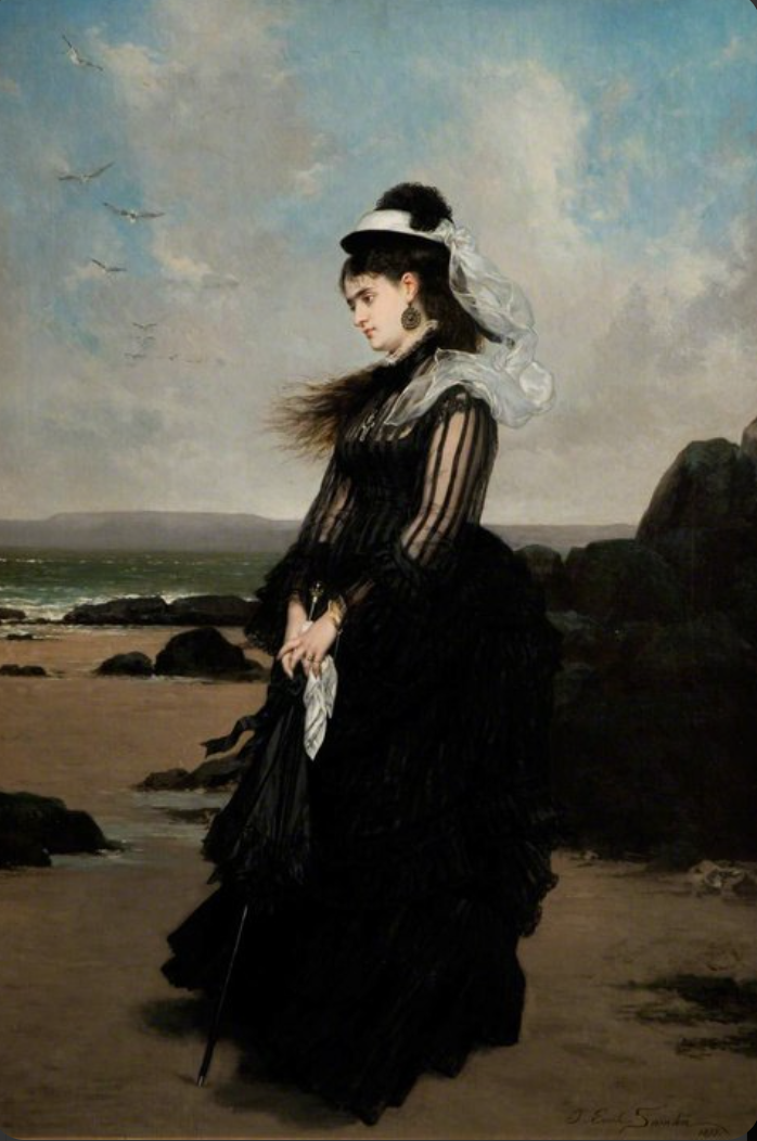 A Victorian woman in full mourning dress on the shore